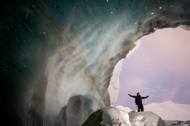 istock Explorer stands in mouth of ice cave 2165283275