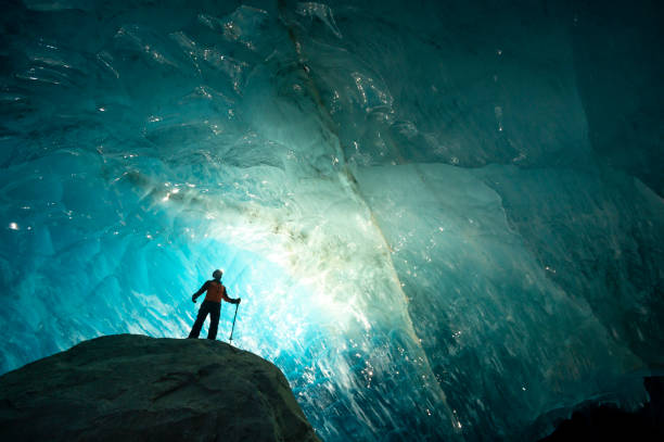 istock Explorer stands in mouth of ice cave at night 2165283383