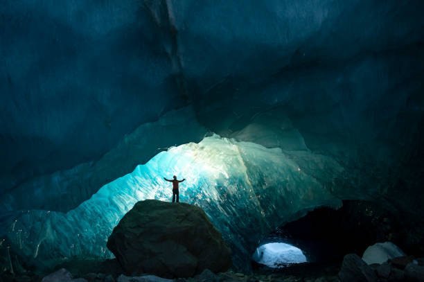 istock Explorer stands in mouth of ice cave at night 2165283384