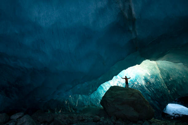 istock Explorer stands in mouth of ice cave at night 2165283385
