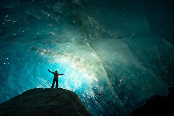 istock Explorer stands in mouth of ice cave at night 2165283386