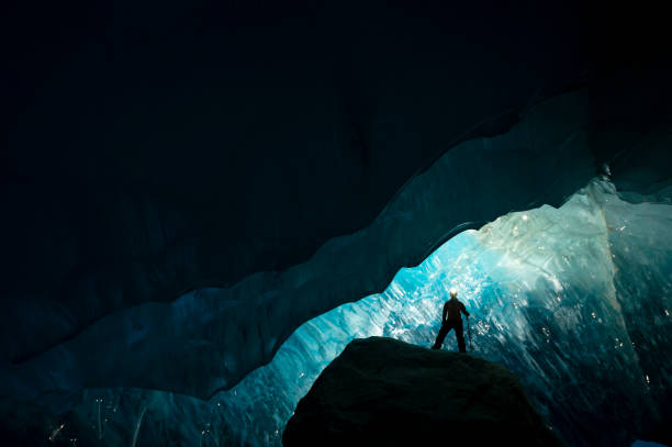 istock Explorer stands in mouth of ice cave at night 2165283505