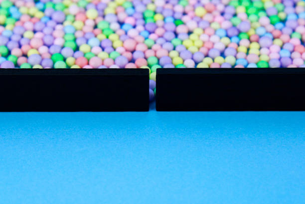 Spheres of different colors concentrated behind a wall formed with black rectangular wooden figures