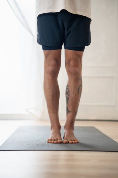 istock Man standing barefoot in yoga mat at home 2165285172