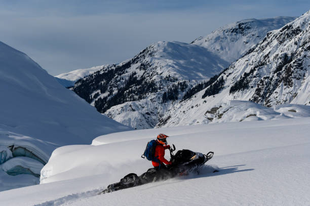 Backcountry snowmobiler rides across glacier