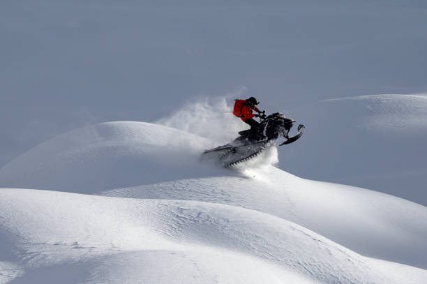 red snowmobile on a background of snowy mountains on a sunny day.