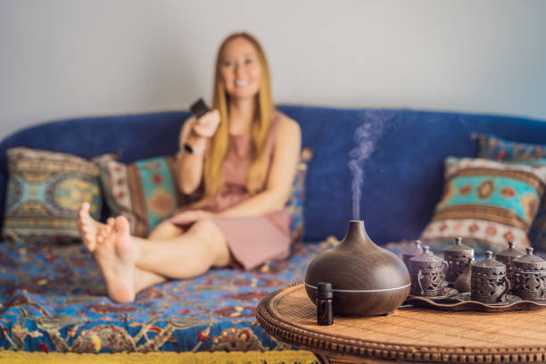 istock Aromatherapy Concept. Wooden Electric Ultrasonic Essential Oil Aroma Diffuser and Humidifier. Ultrasonic aroma diffuser for home. Woman resting at home 2165287308