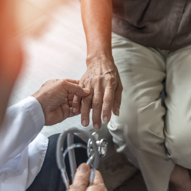 Parkinson disease, Arthritis or elderly patient, old aged senior woman holding geriatric doctor, cargiving nurse or family assistant's hand in hospice home for medical health care or mental therapy stock photo