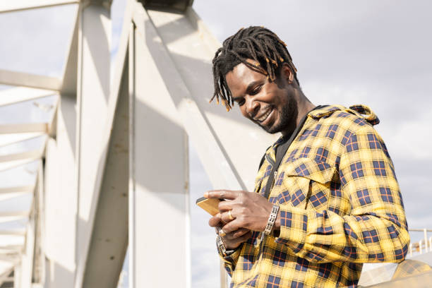 istock smiling young black man looking his mobile phone 2165293326