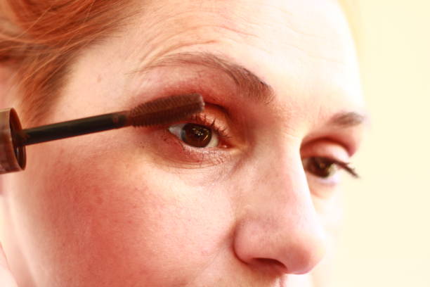 istock Woman Applying Mascara to her Eyelashes 2165295625