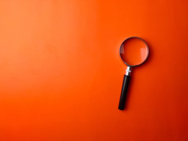 istock Top view magnifying glass on a orange background 2165305050