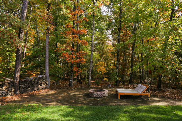 istock Charming Fire Pit In Backyard Beside A Lone Lounge Chair By Stacked Wood 2165306155
