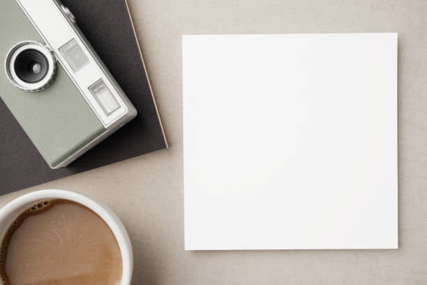 istock Blank white greeting card or invitation with coffee cup, camera and notebook on beige background. Mockup presentation. Flat lay. 2165308116