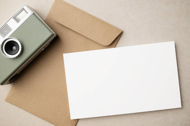 istock White blank greeting or invitation card and envelope with coffee cup, notebook and pencil on beige background. Mockup presentation. Flat lay. 2165308143