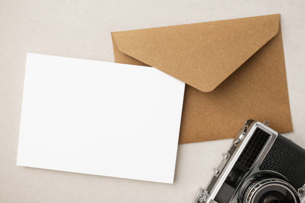 istock White blank greeting or invitation card and envelope with coffee cup, notebook and pencil on beige background. Mockup presentation. Flat lay. 2165308146