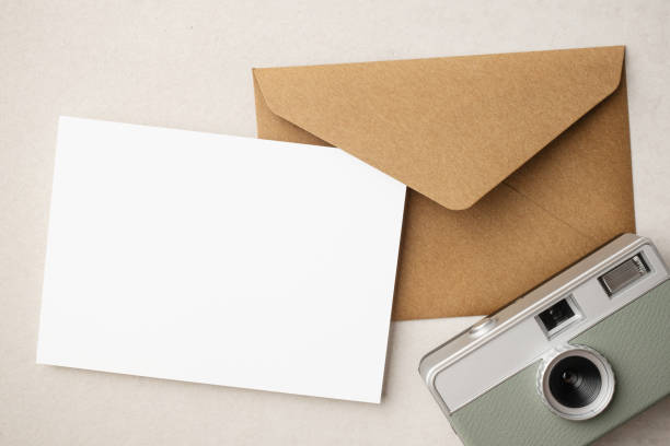 istock White blank greeting or invitation card and envelope with coffee cup, notebook and pencil on beige background. Mockup presentation. Flat lay. 2165308147