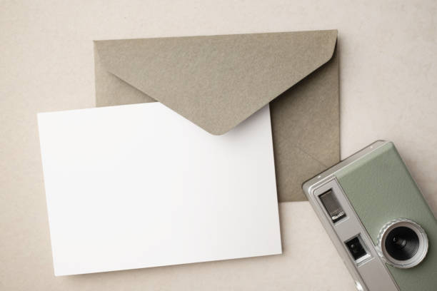 istock White blank greeting or invitation card and envelope with coffee cup, notebook and pencil on beige background. Mockup presentation. Flat lay. 2165308155