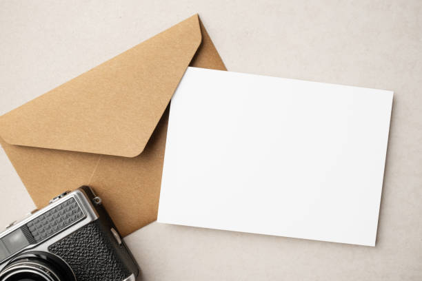 istock White blank greeting or invitation card and envelope with coffee cup, notebook and pencil on beige background. Mockup presentation. Flat lay. 2165308159