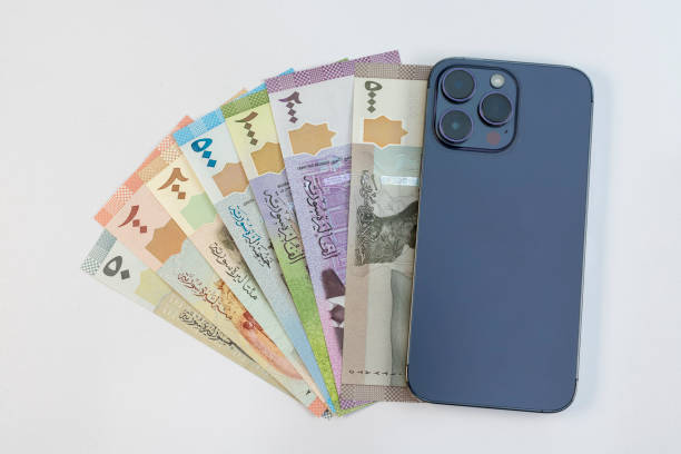 istock Syrian currency notes with smartphone on white background. Mobile banking concept. 2165311462