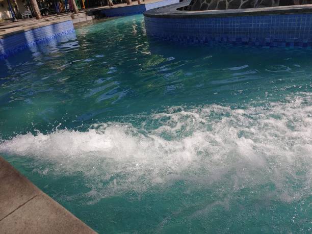 Water running system in swimming pool. Water jets in a swimming pool from a pipe on the surface creating bubbles of different sizes and flying debris