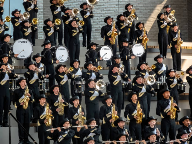 Calgary, Alberta, Canada. Jul 12, 2024. A marching band, clad in black and white uniforms and cowboy hats, performs energetically on tiered stands. Musicians play brass, woodwind and percussions.