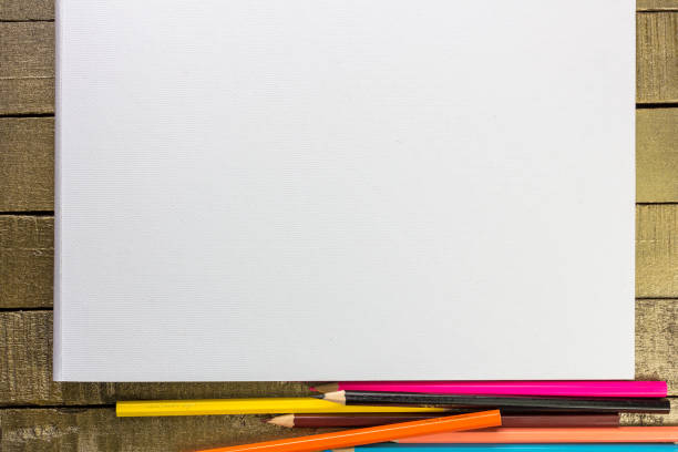 Back to school concept with crayons and paper clip on purple background