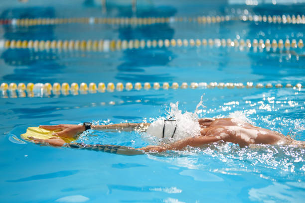 istock Sporty man wearing white cap and goggles cuts through water with precision, fully immersed in his outdoor practice. 2165321582
