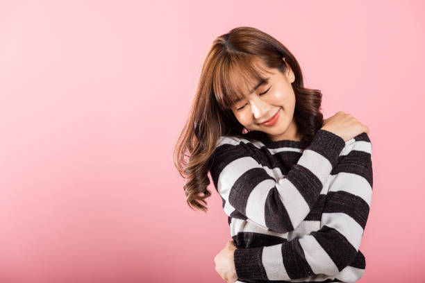 istock Happy beautiful young smiling Asian woman hugging herself remember a moment studio short isolated on pink background 2165322223