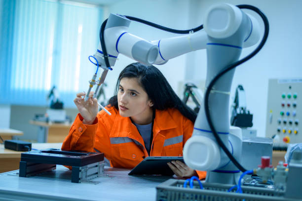 Female Robotics engineer working with Programming and Manipulating Robot Hand, Industrial Robotics Design, High Tech Facility, Modern Machine Learning. Mass Production Automatics. stock photo