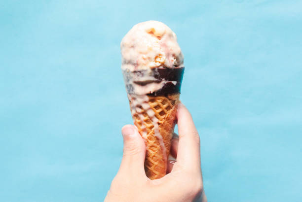 istock hand holding melting ice cream on blue background 2165326071