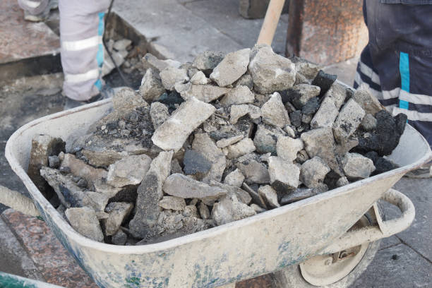 Construction workers dealing with a wheelbarrow overloaded with broken stone and debris.