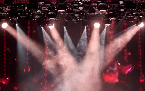 Bright stage lights shining through the smoke and haze with a red background