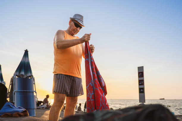 Senior man folding his beach towel and dressing up