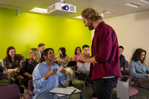 A wide shot of a group of science professionals attending a group seminar in London England, they are leading scientists in their fields of study. The man leading the seminar is talking to one of the members of the audience.\n\nVideos are available similar to this scenario.