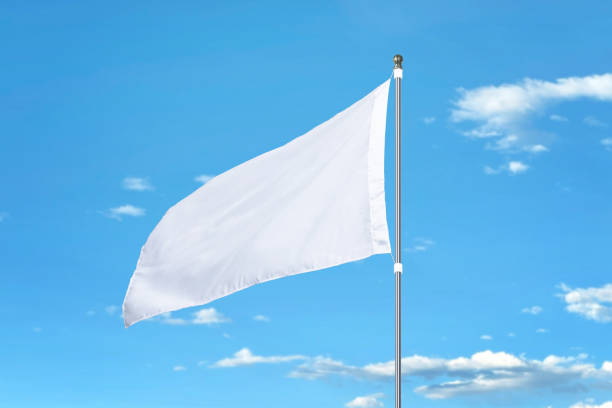 istock White flag fluttering in the wind on a sunny day. Ideal for mockups, adding designs, or national flags. Clear blue sky in the background 2165335813