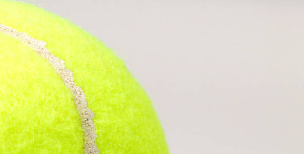 istock Tennis ball in foreground on gray background, space for text. 2165343639