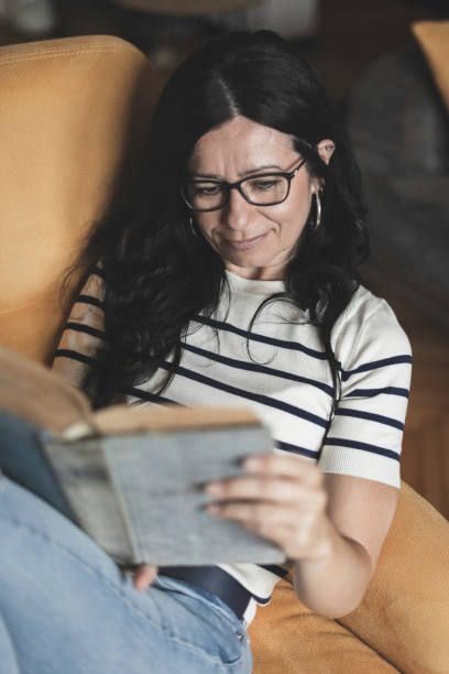 istock A woman reading a book at home 2165344438