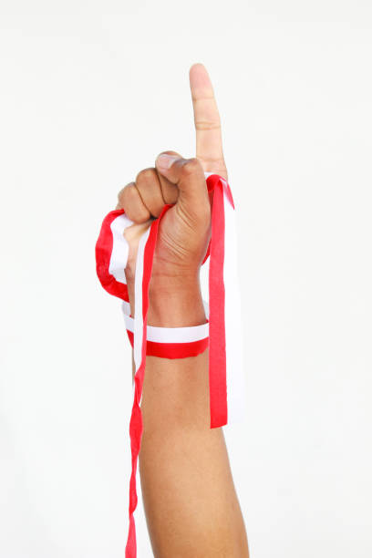 A man with a fist holding a red and white ribbon with empty copy space isolated on a white background, representing Indonesia Independence Day concept. celebrating Indonesia's Independence Day