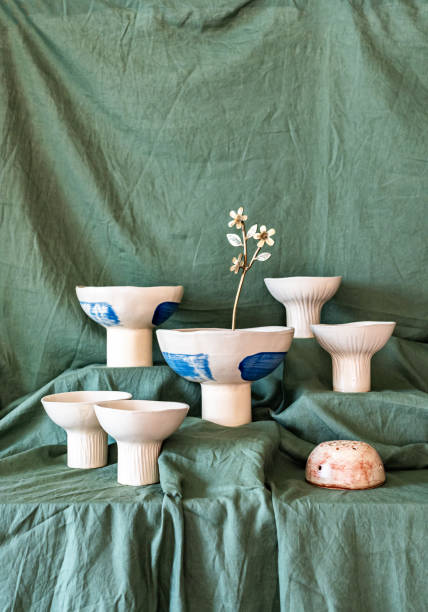 A selection of handmade stoneware ceramics in various glazes and decorations on a soft cloth background and setup