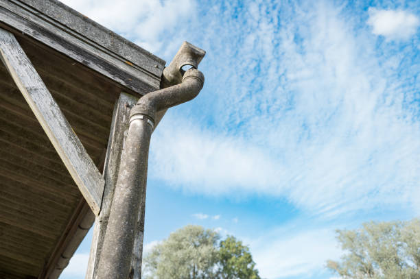Disjointed drain and gutter which is made from asbestos seen attached to an old farm building in the UK. stock photo