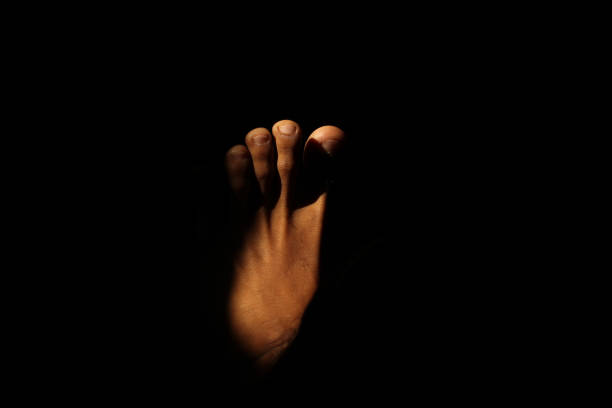 istock Man's feet with sunlight entering a dark room 2165357972