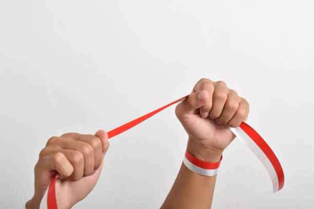 istock Both clenched hands holding red and white ribbon. Indonesian Independence Day concept 2165358928