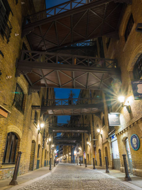 London Thames warehouse apartments overlooking cobbled lane illuminated at night Converted warehouse apartments along a quiet cobbled lane lamplit beside the River Thames in central London, UK. bermondsey street restaurants stock pictures, royalty-free photos & images