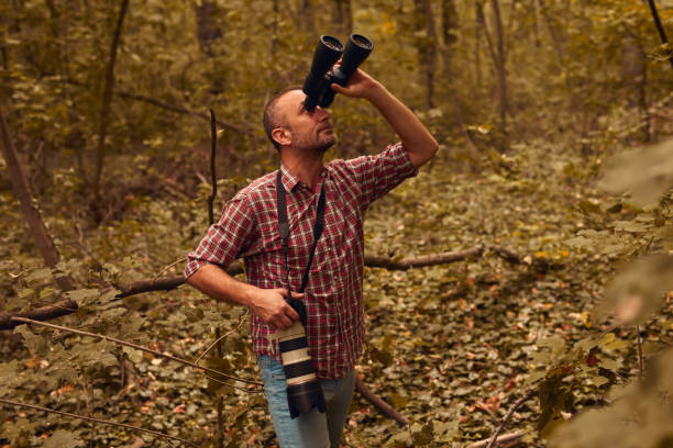 istock Man using binoculars and camera for bird and animal watching in nature. 2165372378