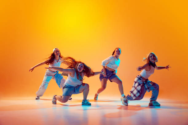 istock Girls dancing synch in vibrant neon light against gradient studio background. Dynamic dance style. 2165378335