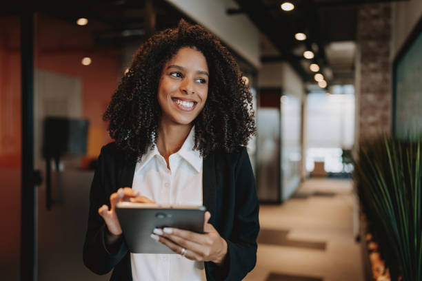 istock Young businesswoman using digital tablet standing in company hallway 2165381036