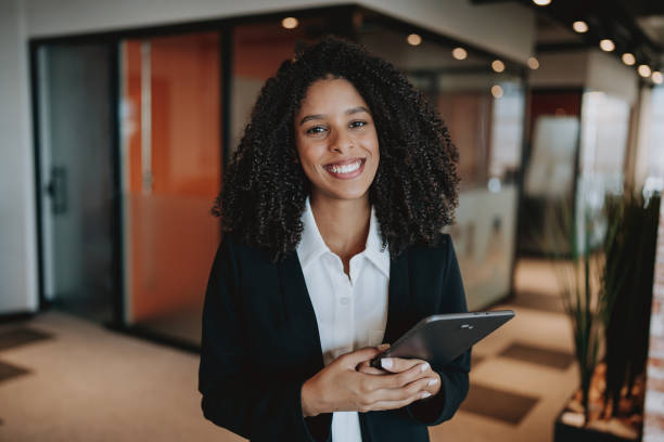 istock Young businesswoman using digital tablet standing in company hallway 2165381131