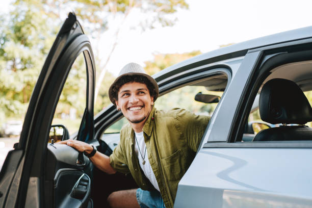 young man traveling by car getting out of the car - conducir fotografías e imágenes de stock