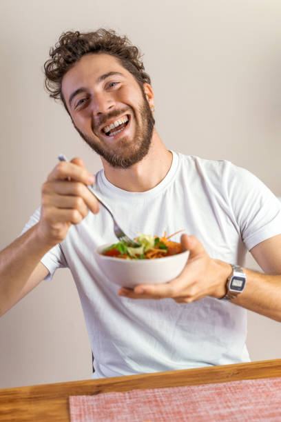 istock Smiling Man Eating Healthy Salad - Enjoying a Nutritional Meal 2165384899