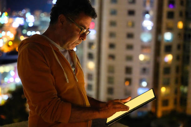 istock Mature Man Using Tablet with City Lights in Background 2165386850
